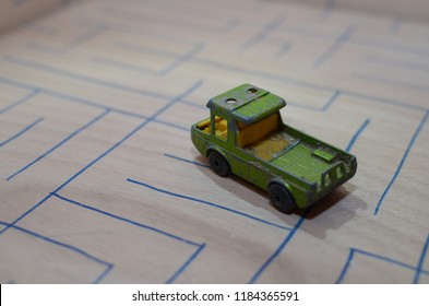 An Old Match Box Toy Car Running On A Wooden Labyrinth Pattern, Designed With A Blue Pen