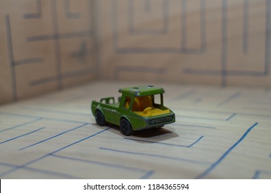 An Old Match Box Toy Car Running On A Wooden Labyrinth Pattern, Designed With A Blue Pen