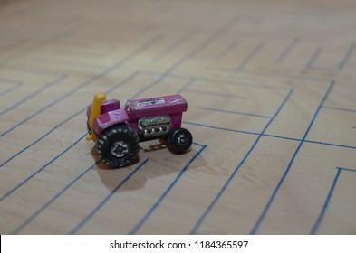 An Old Match Box Toy Car Running On A Wooden Labyrinth Pattern, Designed With A Blue Pen