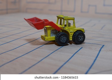 An Old Match Box Toy Car Running On A Wooden Labyrinth Pattern, Designed With A Blue Pen