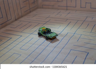 An Old Match Box Toy Car Running On A Wooden Labyrinth Pattern, Designed With A Blue Pen