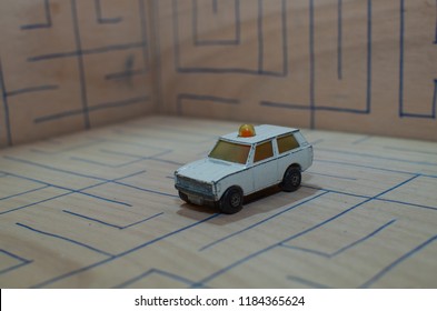 An Old Match Box Toy Car Running On A Wooden Labyrinth Pattern, Designed With A Blue Pen