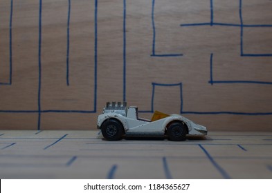 An Old Match Box Toy Car Running On A Wooden Labyrinth Pattern, Designed With A Blue Pen