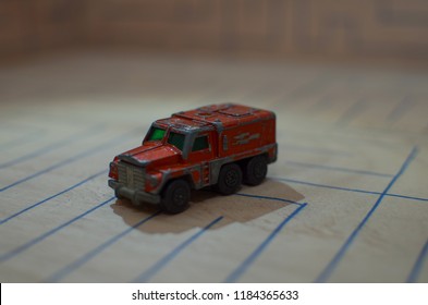 An Old Match Box Toy Car Running On A Wooden Labyrinth Pattern, Designed With A Blue Pen