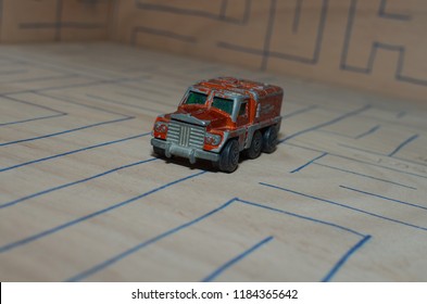 An Old Match Box Toy Car Running On A Wooden Labyrinth Pattern, Designed With A Blue Pen