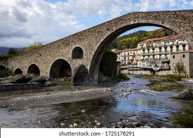 Old medieval bridge made of stones over a small river in a village close to the mountains.
