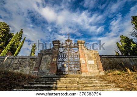 Old medieval cemetery gate and red brick wall in Tuscany, Italy