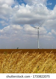 The Old Meets New As A Towering Wind Turbine Flanks An Oilfield Pump Jack Or Pumping Unit.