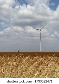 The Old Meets New As A Towering Wind Turbine Flanks An Oilfield Pump Jack Or Pumping Unit.