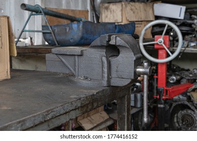 Old Metal Bench Vise On Steel Table At Workshop. Metal Clamps.