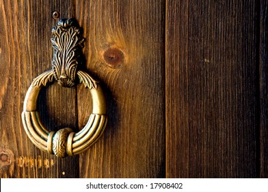 Old metal door handle knocker on a rough wooden background - Powered by Shutterstock