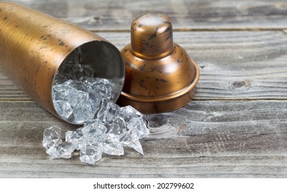 Old Metal Drink Mixer Lying On Side With Crushed Ice Flowing Out Onto Rustic Wood