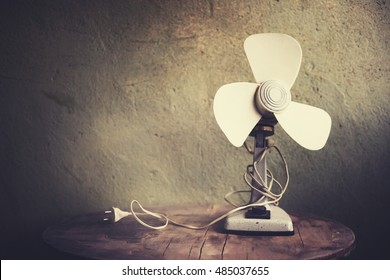 Old metal fan on rustic wall background in vintage color