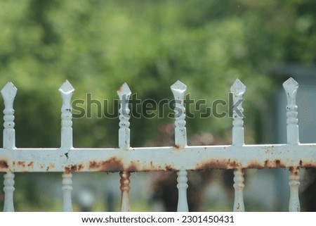 Old metal fence with sharp point in soft blue paint with some rusts