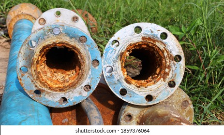 Old metal pipes clogged twin. Suspended solids in water contaminated with iron and manganese cause scale and rust to clog up inside water pipes on a lawn background with a copy area. selective focus