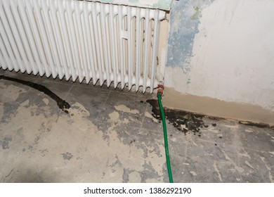 Old metal radiator or finned tube heater on a white stone wall - Shutterstock ID 1386292190