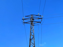An Old Metal Telegraph Pole Against A Blue Sky With No Clouds. Glass Insulators, Wires. A Sunny Day.