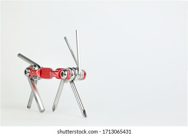 Old Metallic Red Bike Multi-tool Is Going To Fix, Repair And Service On A White Background. Bicycle Multifunction Hand Tool Like An Animal With 4 Legs, Tail And 2 Horns. Animal Robot For Bike Help.