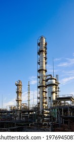 Old Methanol Distillation Refinery Column Towers And Reactors Under Blue Evening Sunset Sky Background At Chemical Plant. Exterior Of Silver Metal Rusty Enterprise 16x9 Vertical With Copyspace.