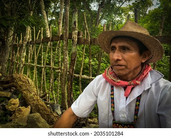 Old Mexican man with hat and white shirt sitting in front of a wood fence in Coba, Quintana Roo, Mexico on September 20th 2020