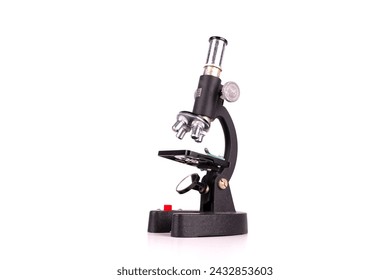 an old microscope stands isolated on a white background on a white surface with real shadows
