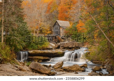 An old mill situated behind a waterfall surrounded by autumn foliage New River Gorge National Park