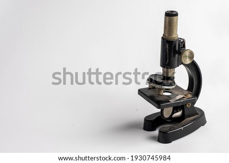 An old miniature microscope in a white background. Copy space of an miniature microscope.