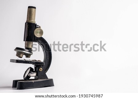 An old miniature microscope in a white background. Copy space of an miniature microscope.