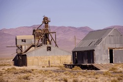 Old Mining Buildings, Rusting In The Desert,with Mountains In Background, Nevada