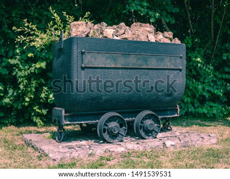 Old mining trolley minecart loaded with stones stands on rails