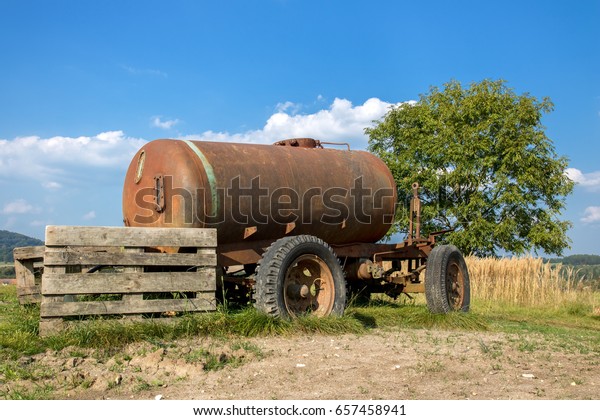 Old mobile cistern with\
water on the countryside. Abandoned old rusty car trailer tank in\
the field.