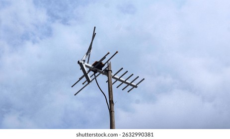 Antena vieja de la televisión modelo (TV) en la parte superior de la casa con el fondo azul nublado del cielo, antena analógica