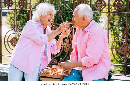 Old modern couple dressing fashionable colored clothes. Youthful grandmother and grandfather having fun outdoor and going wild. Representation of elderly people feeling young inside - Powered by Shutterstock