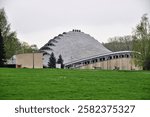 An old modernist building with curved shapes, low in a park with green grass