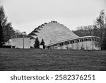 An old modernist building with curved shapes, low in a park black and white