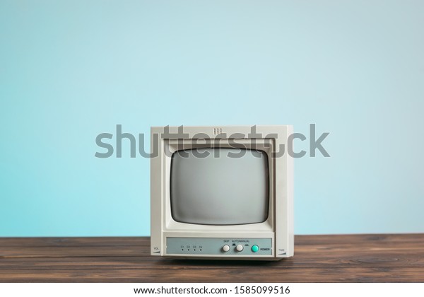 The old monitor on a wooden table on a blue\
background. Vintage\
electronics.