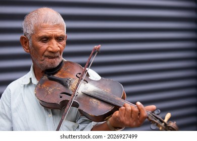 An Old Musician Man With Wrinkle Face And Sparse Gray Hair Playing The Violin Using The Violin Bow On The Street, He Loves His Occupation.