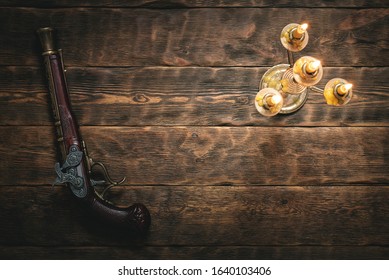 Old musket gun on pirate desk table in the light of burning candle concept background with copy space.