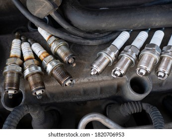 Old And New Car Spark Plugs On Engine Background