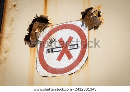 Old no smoking pictorial sign on a rotten and rusty metal wall