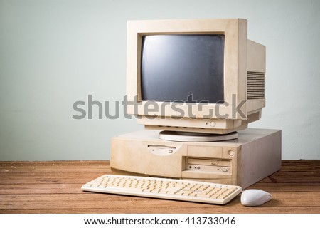 old and obsolete computer on old wood table with concrete wall background