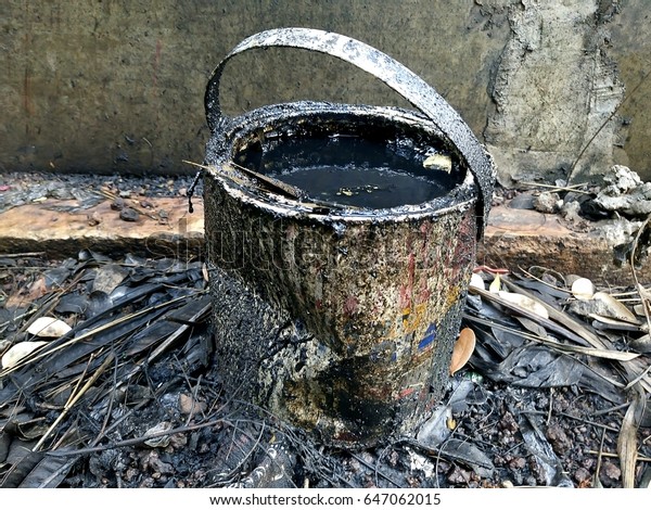 Old oil\
of car motor engine. Engine oil in a metal canisters with dirty\
cement wall background. Overflowing black motor oil from container\
to the ground. - Environmental pollution\
concept.