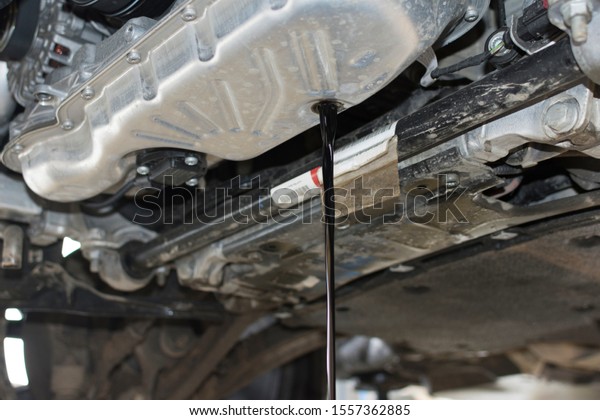 The old oil is drained from the car engine. Car\
maintenance. The car engine is bottom view. Oil change in the\
engine. Car service.