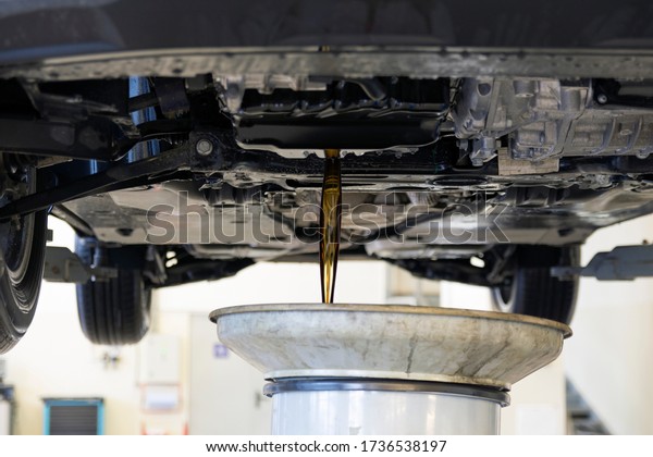 Old oil is drained from the car engine. Car\
maintenance. Car engine bottom view. Changing the engine oil. Car\
service interior