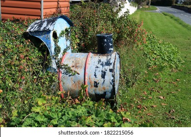 An Old Oil Drum Converted Into A Model Train Engine With Peeling Paint On A Grass Verge By A Road In West Wales, UK. 