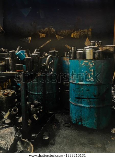 Old oil tank in the garage,engine oil and oil\
cans in a car garage.