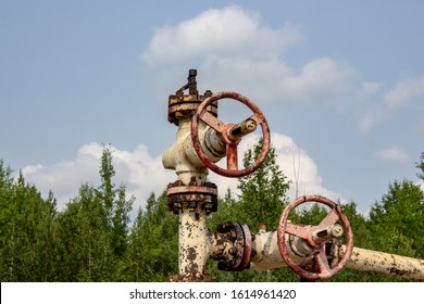 Old Oil Well Valve On The Background Of Clouds And Forest