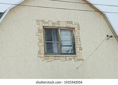 old one square window on the brown light concrete wall of the building