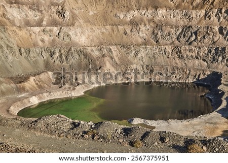 Old open mining pit in mountain. Open-pit quarry, mine landscape, pond. Historical travel destination place Ak-Tyuz, Kyrgyzstan. Abandoned Kyrgyz mining and metallurgical plant. lead mining, deposit