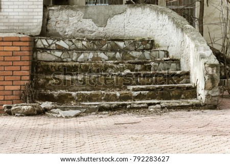 An old open outer stone staircase. Stone, cement steps of the old staircase with traces of weathering and destruction. An ancient stone staircase, ancient broken worn steps. Selective focus